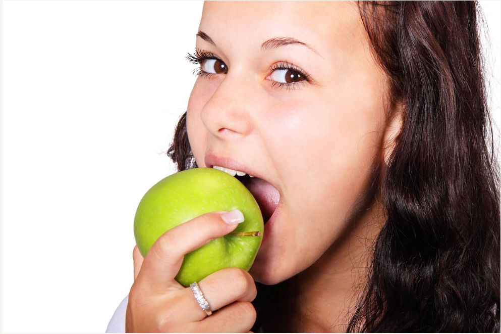 Woman taking bite out of a green apple Norridge Dentist